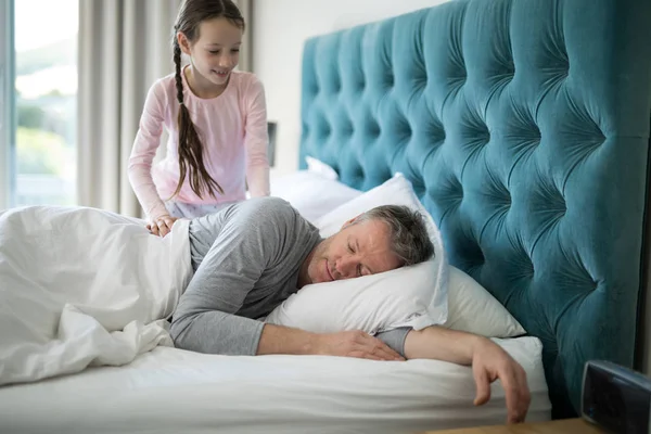 Девочка будит спящего отца в постели — стоковое фото
