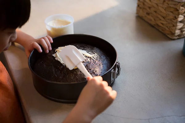 Menina espalhando creme no bolo — Fotografia de Stock