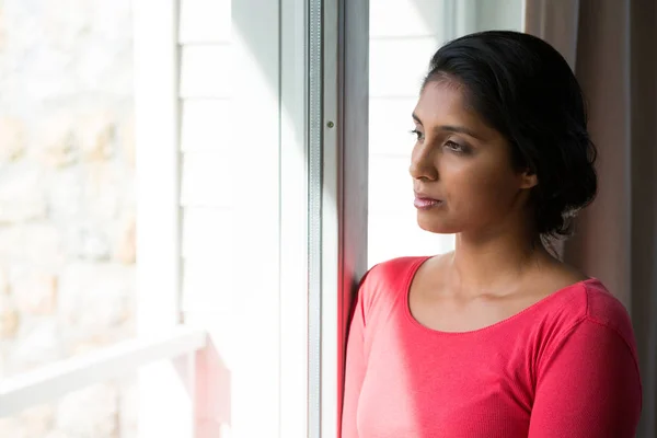 Tankfull ung kvinna tittar genom fönstret — Stockfoto