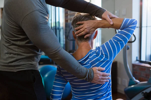 Fisioterapeuta auxiliando a mulher idosa no exercício — Fotografia de Stock