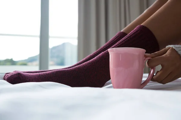 Mulher com xícara de café relaxante na cama — Fotografia de Stock