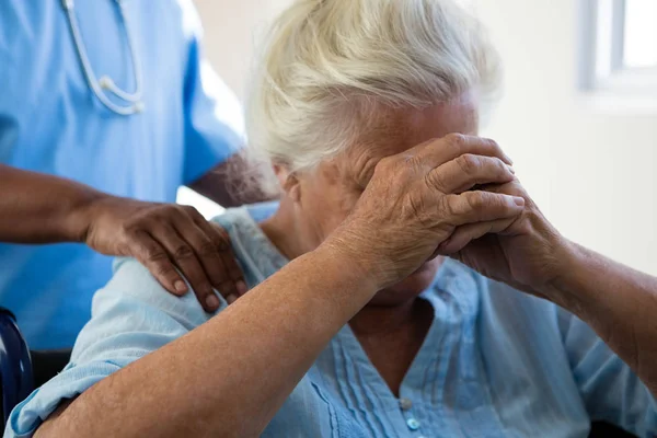 Verpleegkundige troostende senior vrouw bij verpleeghuis — Stockfoto