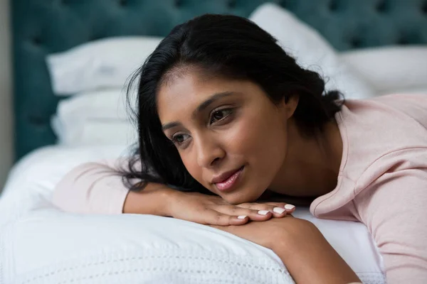 Thoughtful woman relaxing on bed — Stock Photo, Image