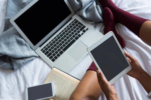 Wanita menggunakan tablet digital oleh laptop di tempat tidur — Stok Foto