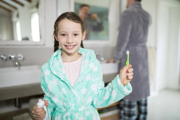 Meisje bedrijf tandpasta en tandenborstel — Stockfoto