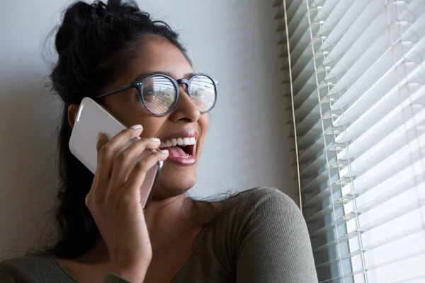 Gelukkige vrouw praten over telefoon door raam — Stockfoto