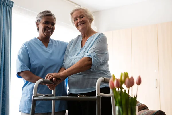 Nurse standing by senior woman holding walker — Stock Photo, Image