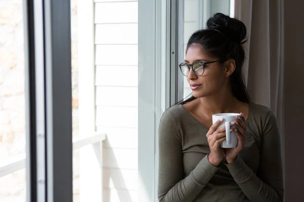 Kobieta z filiżanki kawy przez okno — Zdjęcie stockowe