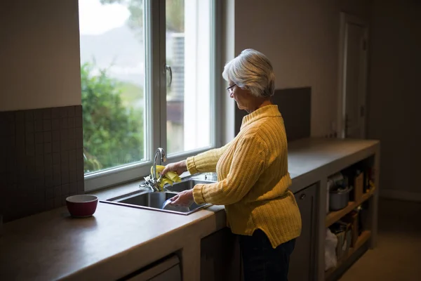 Senior kobieta mycia naczynia w zlewie — Zdjęcie stockowe