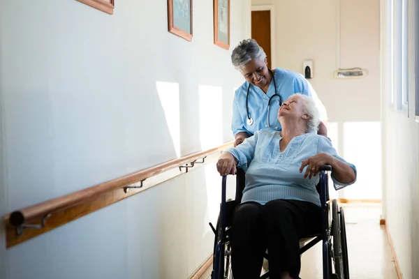 Sjuksköterska driftigt patienten sitter i rullstol — Stockfoto
