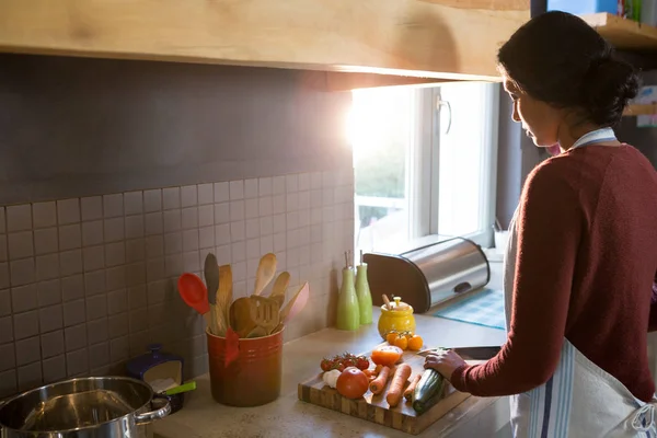 Mujer cortando calabacín en la cocina —  Fotos de Stock