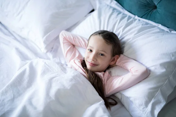 Smiling girl lying on bed in bedroom — Stock Photo, Image