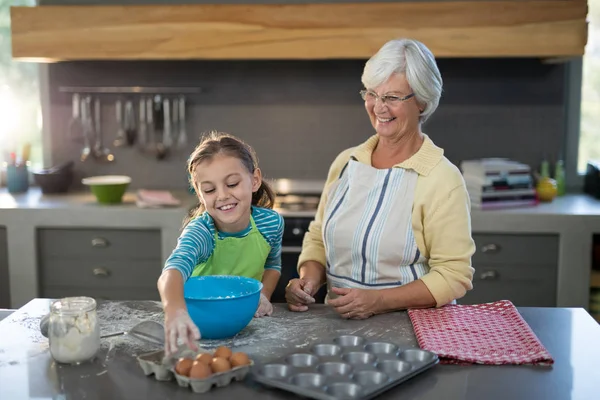 Granddaughter picking up eggs and grandmother smiling — Stock Photo, Image