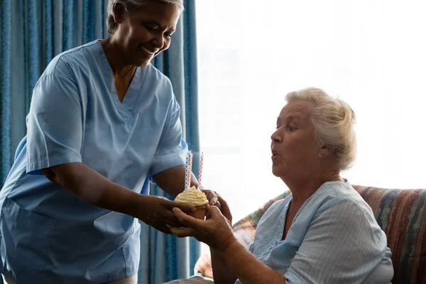 Senior Kvinna blåser ljus av kaka — Stockfoto