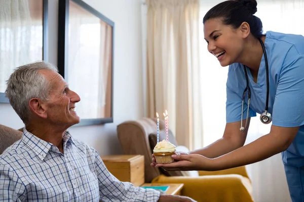 Senior man kijken naar arts holding cup cake — Stockfoto