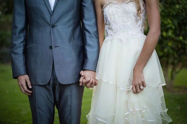 Hochzeitspaar hält Händchen im Garten — Stockfoto