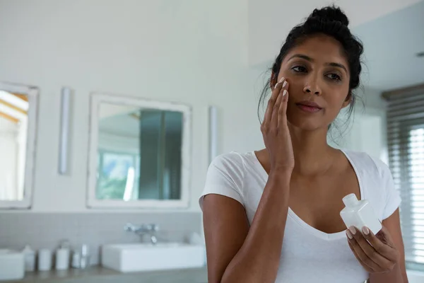 Vrouw toepassing lotion in badkamer — Stockfoto