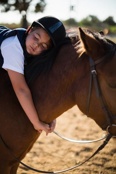 Menino abraçando cavalo no rancho — Fotografia de Stock
