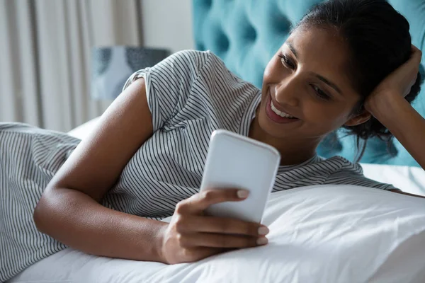 Γυναίκα με τη χρήση του τηλεφώνου ενώ χαλαρώνετε στο κρεβάτι — Φωτογραφία Αρχείου