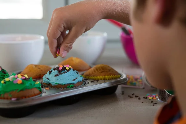 Cropped hand of boy decorating cupcakes — Stock Photo, Image