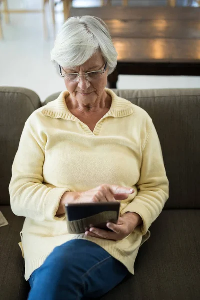 Mulher idosa usando tablet no sofá — Fotografia de Stock