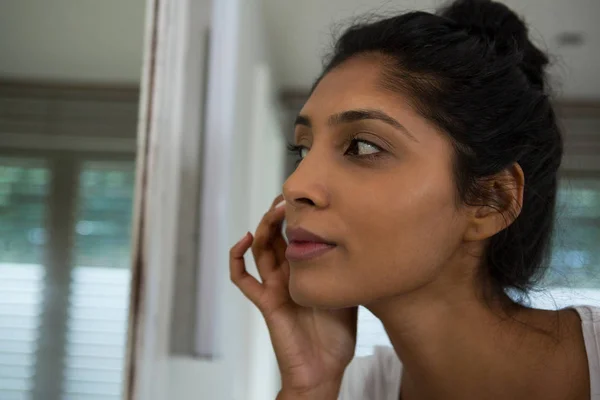 Woman touching face by mirror — Stock Photo, Image