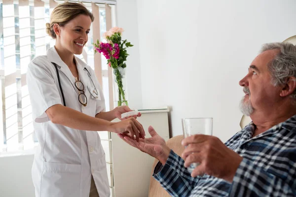 Женщина-врач дает лекарства пожилым пациентам — стоковое фото
