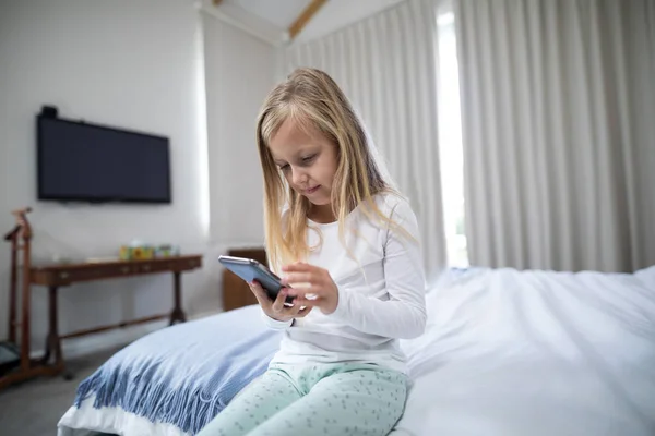 Meisje met telefoon op bed in de slaapkamer — Stockfoto
