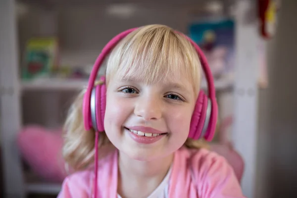 Söpö tyttö kuuntelee vaaleanpunainen kuulokkeet — kuvapankkivalokuva