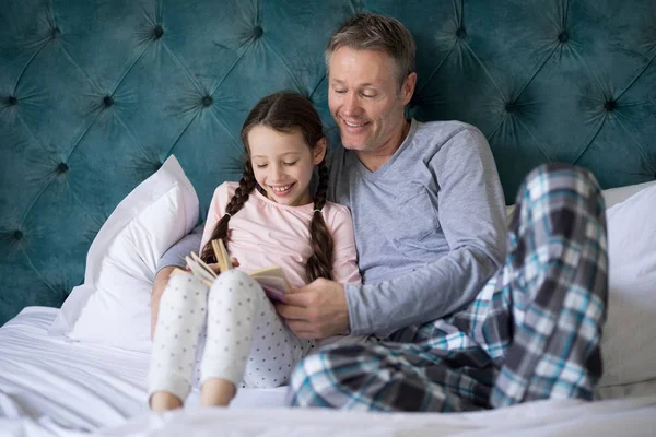 Pai e filha lendo livro na cama — Fotografia de Stock