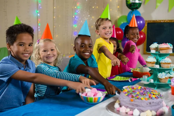 Retrato de niños apuntando a la torta — Foto de Stock