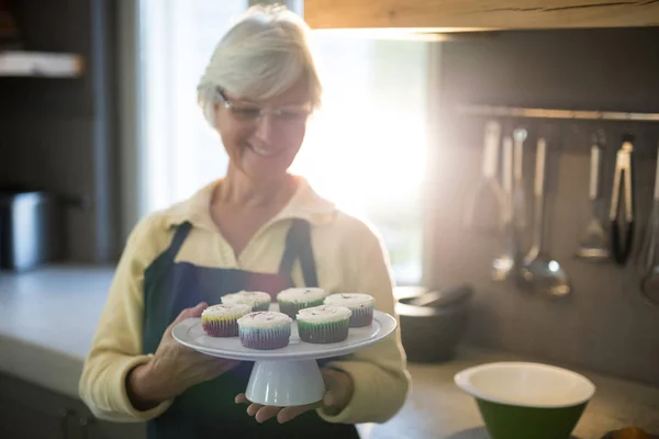 Senior woman holding a tray of cupcakes — Stock Photo, Image