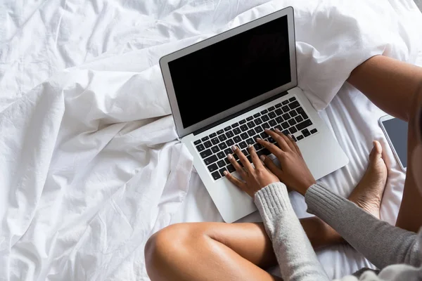 Mujer usando el ordenador portátil mientras se relaja en la cama — Foto de Stock