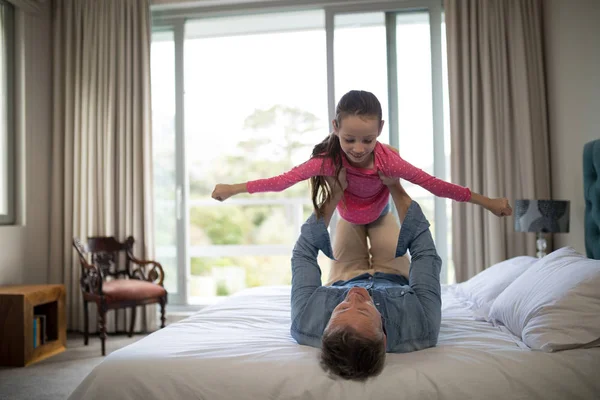 Hravá otec, který zvedá její dcera na posteli — Stock fotografie
