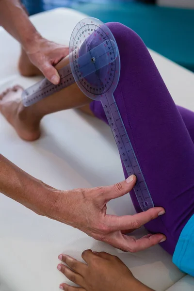 Fisioterapeuta examinando menina pacientes perna — Fotografia de Stock