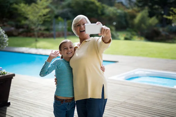 Petite-fille et grand-mère prenant selfie près de la piscine — Photo