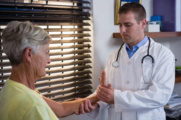 Физиотерапевт осматривает руку пожилого пациента — стоковое фото