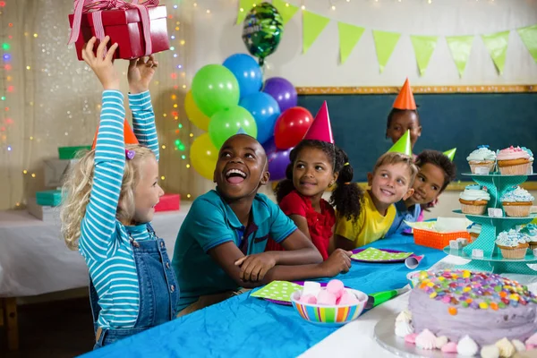 Niños mirando a chica sosteniendo regalo — Foto de Stock