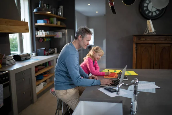 Padre usando el ordenador portátil mientras que la hija es para colorear — Foto de Stock