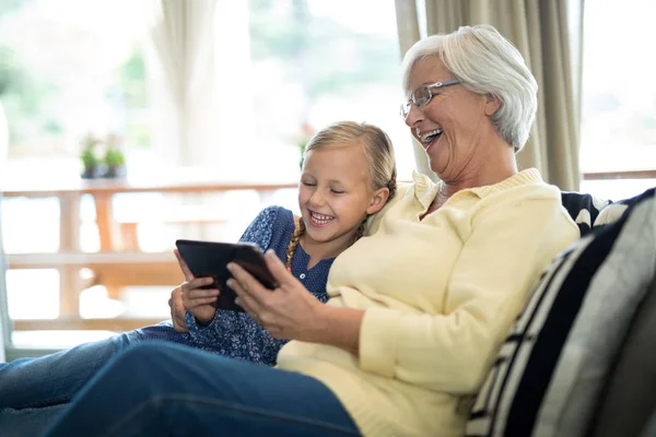 Nieta y abuela usando la tableta en el sofá —  Fotos de Stock