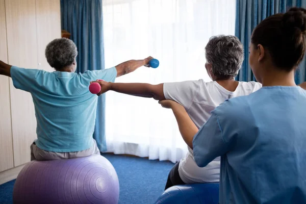Enfermeiro treinando idosos em levantar halteres — Fotografia de Stock