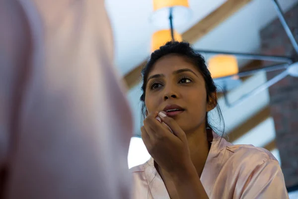 Mujer aplicando brillo labial reflejándose en el espejo — Foto de Stock