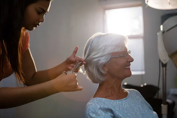 Coiffeur couper les cheveux de la femme âgée — Photo