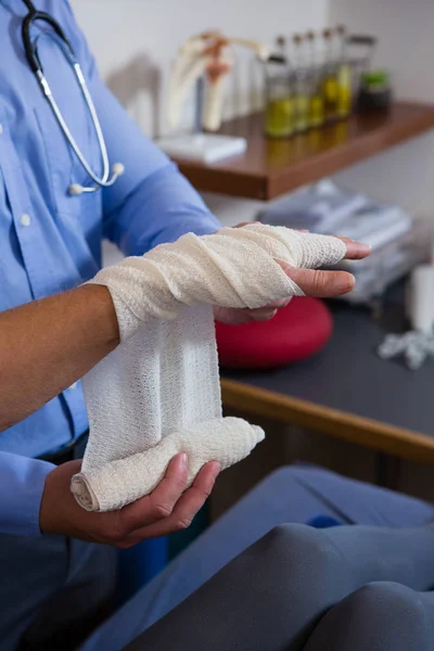 Fisioterapeuta poniendo vendaje en la mano lesionada — Foto de Stock