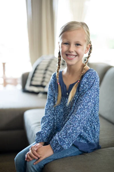 Sorrindo menina sentada no sofá na sala de estar — Fotografia de Stock