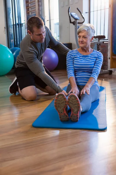 Физиотерапевт, помогающий пожилой женщине в упражнениях — стоковое фото