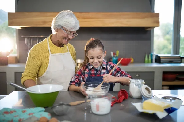 Granddaughter mixing flour in a bowl — Stock Photo, Image