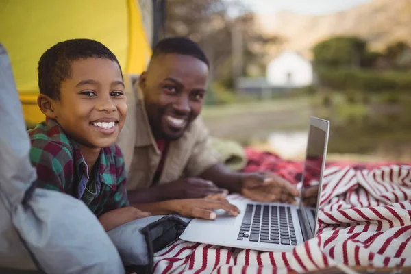 Far och son med laptop i tält — Stockfoto