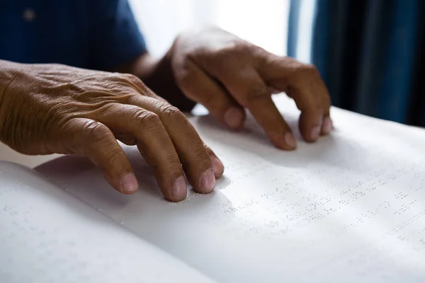 Mains coupées sur un retraité lisant un livre en braille — Photo