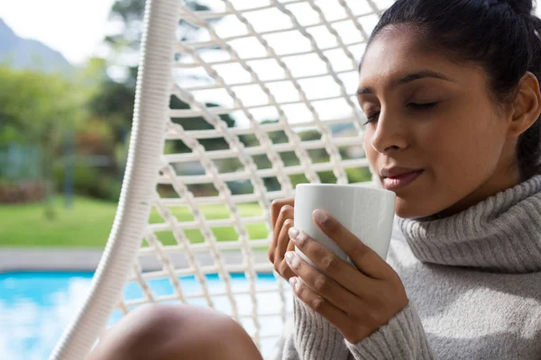Woman holding coffee cup in swing chair — Stock Photo, Image